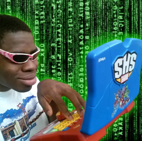 A kid in pink sunglasses typing on a toy laptop in front of green Matrix code